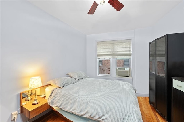 bedroom with ceiling fan, cooling unit, and light wood-type flooring