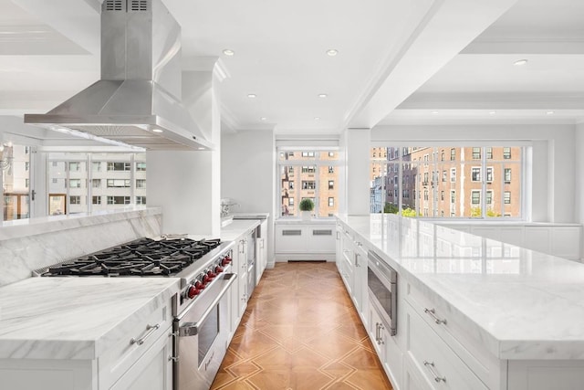 kitchen featuring island exhaust hood, appliances with stainless steel finishes, light stone countertops, and white cabinets