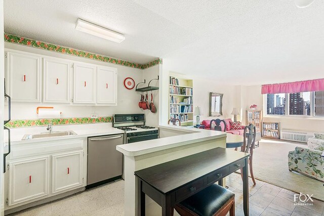 kitchen featuring stainless steel dishwasher, sink, white gas stove, and white cabinetry