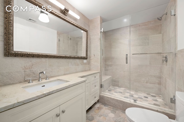 bathroom featuring visible vents, decorative backsplash, toilet, a shower stall, and vanity