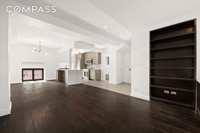 unfurnished living room featuring hardwood / wood-style flooring, recessed lighting, a notable chandelier, a sink, and built in features