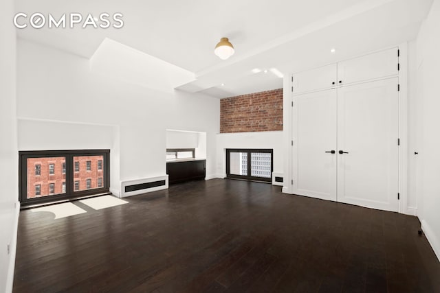 unfurnished living room with dark wood-type flooring, a high ceiling, and baseboards