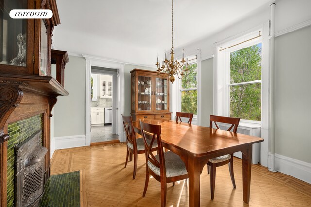 dining room with baseboards, light wood-style floors, a chandelier, and a fireplace