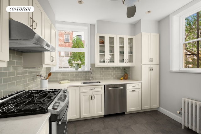 kitchen featuring radiator, light countertops, appliances with stainless steel finishes, white cabinets, and a sink