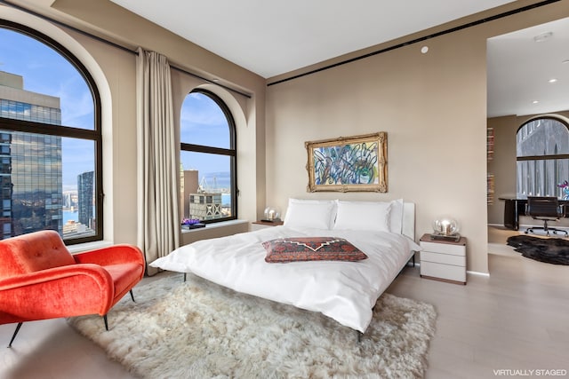 bedroom with a city view, wood finished floors, and recessed lighting