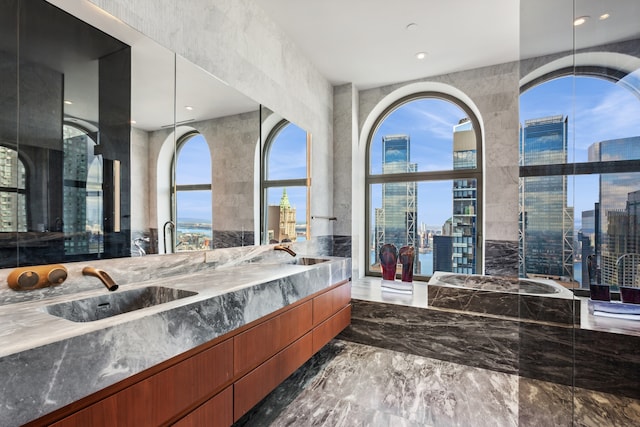 bathroom with marble finish floor, a view of city, a sink, and double vanity