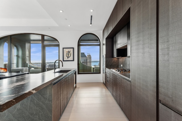 kitchen with a sink, modern cabinets, dark brown cabinets, and recessed lighting