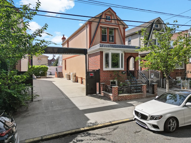 view of front of property featuring a fenced front yard, brick siding, driveway, a gate, and stucco siding