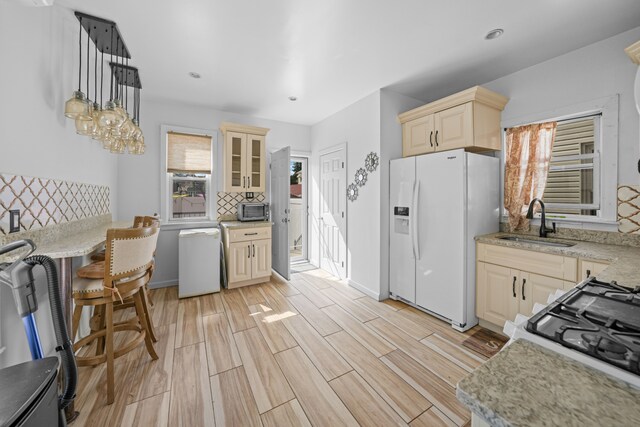 kitchen with decorative light fixtures, tasteful backsplash, glass insert cabinets, a sink, and white appliances