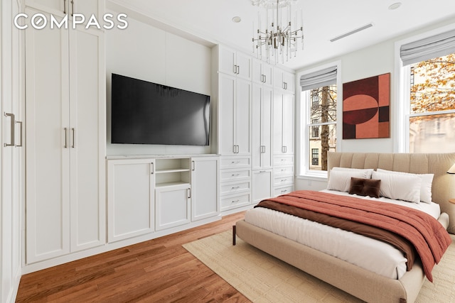 bedroom with an inviting chandelier, wood finished floors, and visible vents