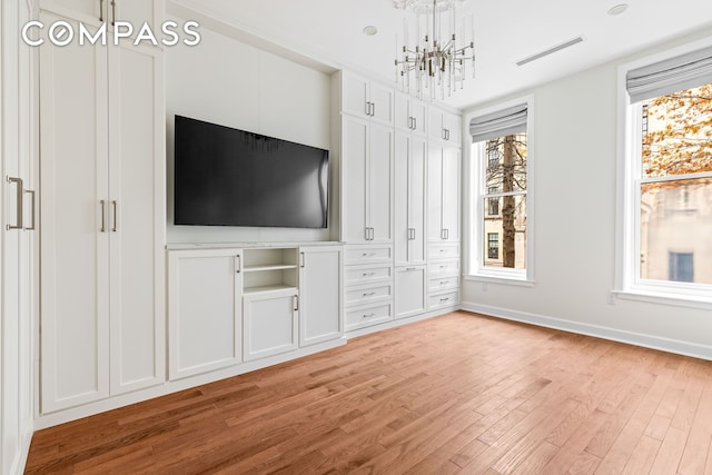 unfurnished living room with light wood-type flooring, baseboards, visible vents, and a chandelier