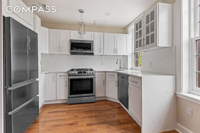 kitchen featuring decorative light fixtures, white cabinetry, stainless steel appliances, and sink