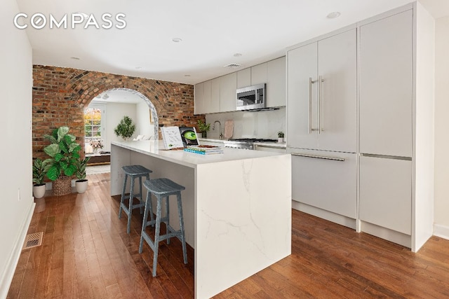 kitchen with hardwood / wood-style flooring, white cabinetry, a kitchen island, and range