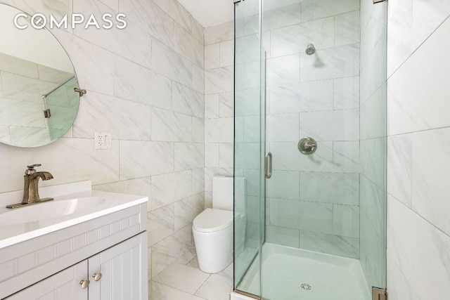 bathroom featuring toilet, tile walls, a shower with shower door, and vanity