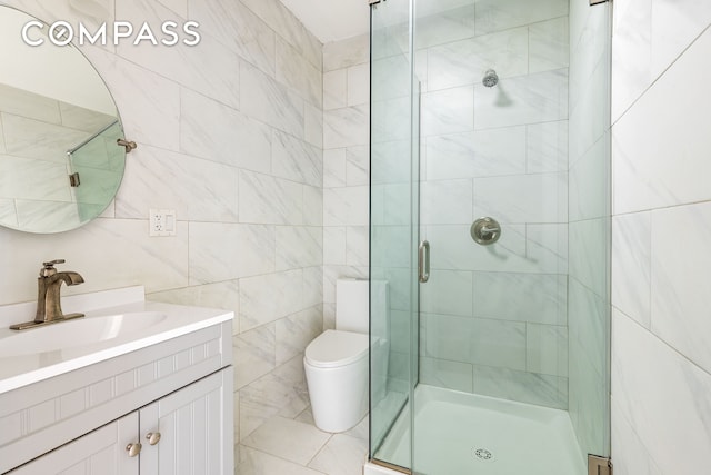 bathroom with vanity, a shower stall, toilet, and tile walls