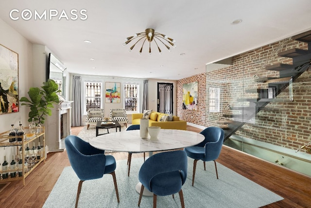 dining space with light wood-type flooring and brick wall