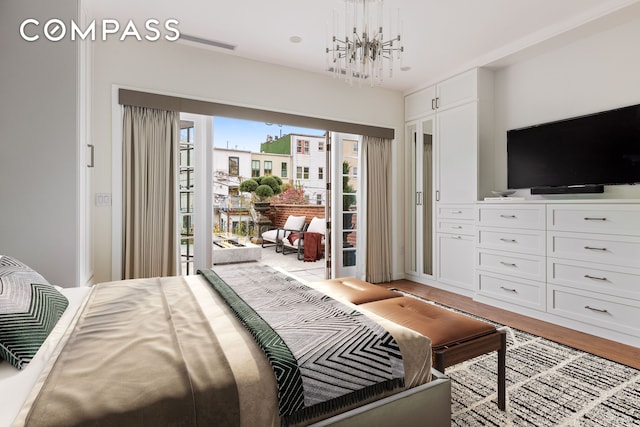 bedroom with light wood finished floors, an inviting chandelier, and access to outside