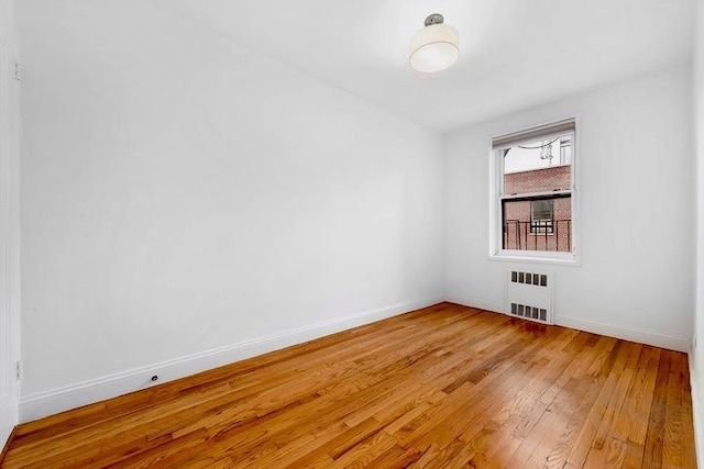 unfurnished room featuring hardwood / wood-style flooring and radiator