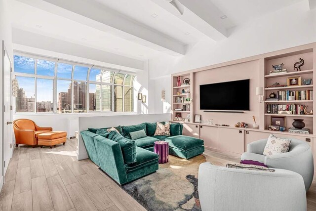 living room with light hardwood / wood-style floors, built in shelves, and beamed ceiling