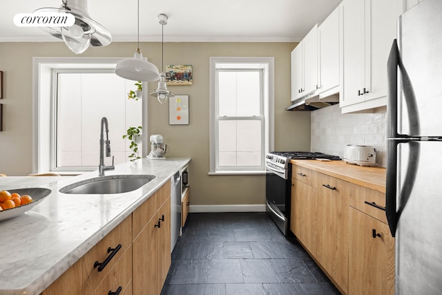 kitchen featuring tasteful backsplash, baseboards, appliances with stainless steel finishes, under cabinet range hood, and a sink