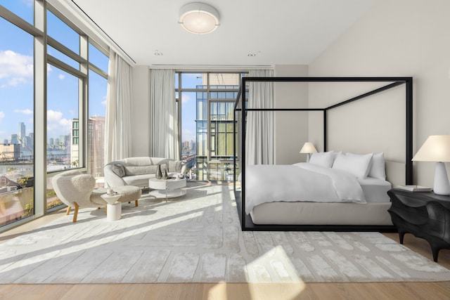 bedroom with access to outside, floor to ceiling windows, a city view, and light wood-style flooring