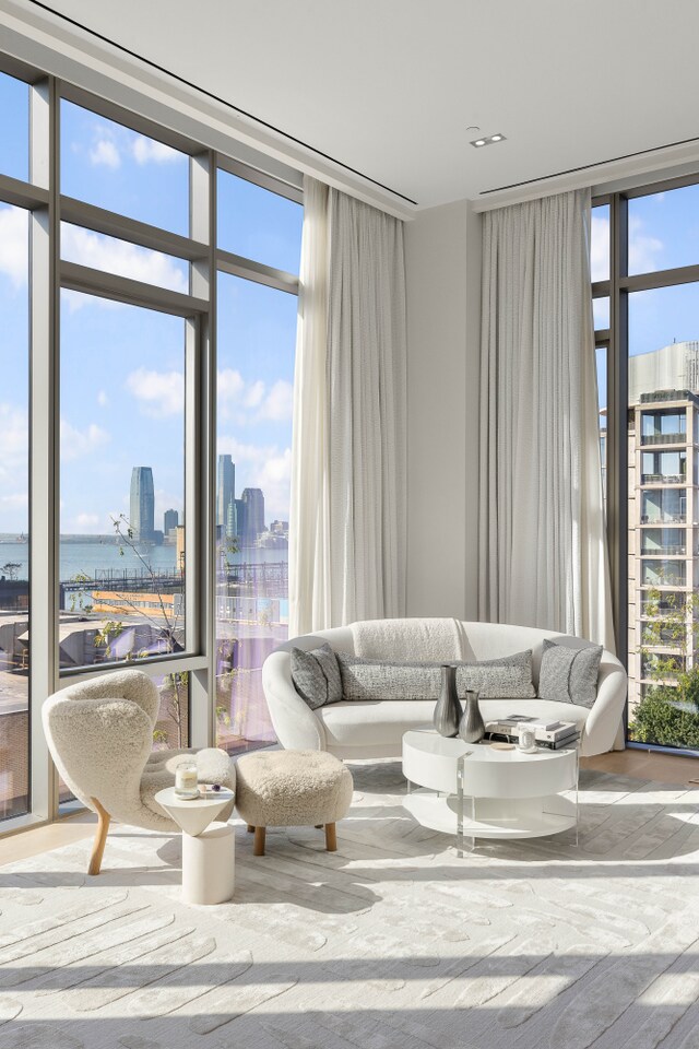 living area with expansive windows, a water view, wood finished floors, and a city view