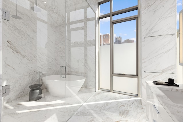 full bathroom with a freestanding bath, marble finish floor, a marble finish shower, and stone wall