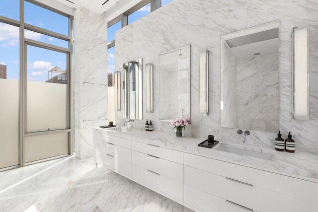 full bath with double vanity, stone wall, marble finish floor, and a sink