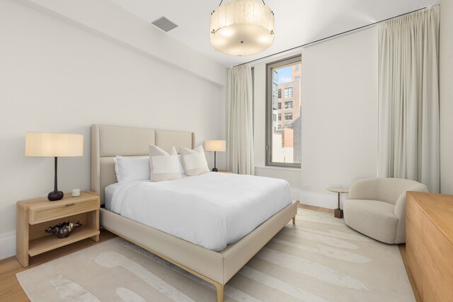 bedroom featuring baseboards, visible vents, and light wood finished floors