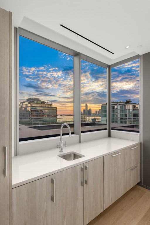 kitchen featuring a sink, light countertops, light brown cabinets, and a city view