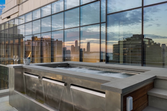 patio terrace at dusk with a city view and a hot tub