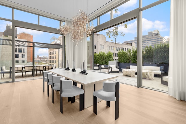 dining area with expansive windows, light wood-style floors, a chandelier, and a city view