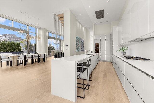 kitchen featuring a breakfast bar area, white cabinetry, light countertops, modern cabinets, and stainless steel gas stovetop