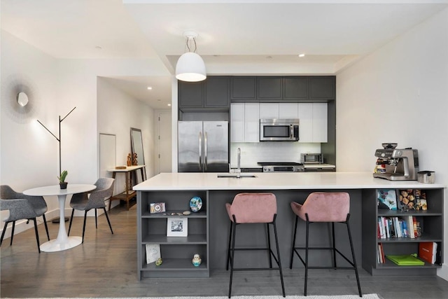 kitchen featuring appliances with stainless steel finishes, decorative light fixtures, tasteful backsplash, sink, and a kitchen bar