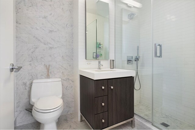 bathroom with tile walls, an enclosed shower, vanity, and toilet