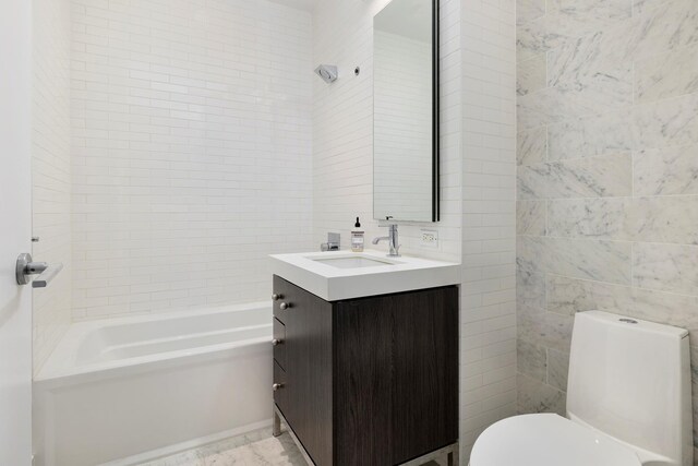 full bathroom featuring tiled shower / bath, vanity, toilet, and tile walls