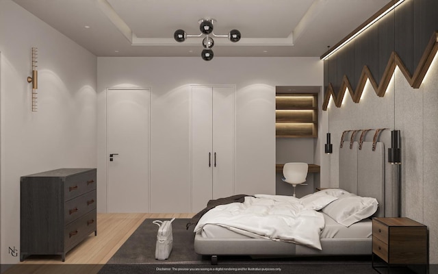 bedroom with light wood-type flooring and a tray ceiling