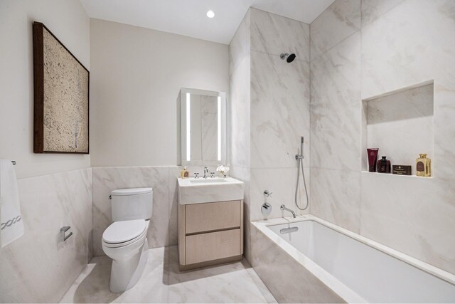 full bath featuring toilet, a combined bath / shower with marble appearance, vanity, and tile walls