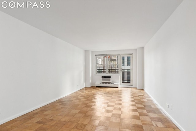 unfurnished living room featuring light parquet floors, an AC wall unit, and baseboard heating