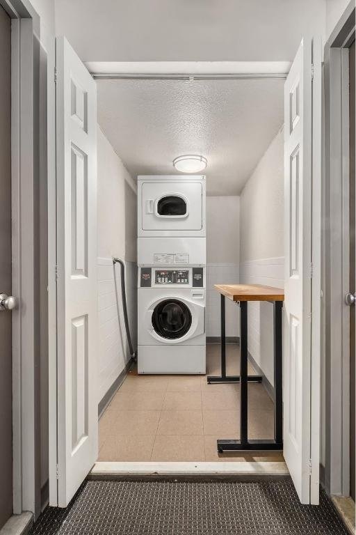 laundry room featuring stacked washer and dryer and a textured ceiling