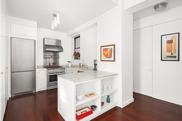 kitchen with wall chimney exhaust hood, white cabinetry, stainless steel appliances, sink, and kitchen peninsula