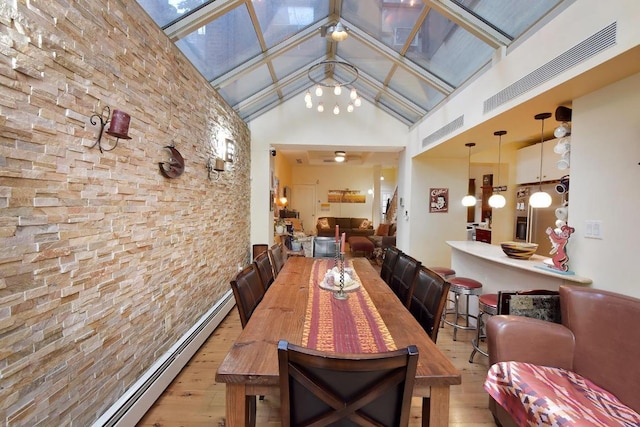 dining area with light hardwood / wood-style flooring, high vaulted ceiling, and a baseboard heating unit