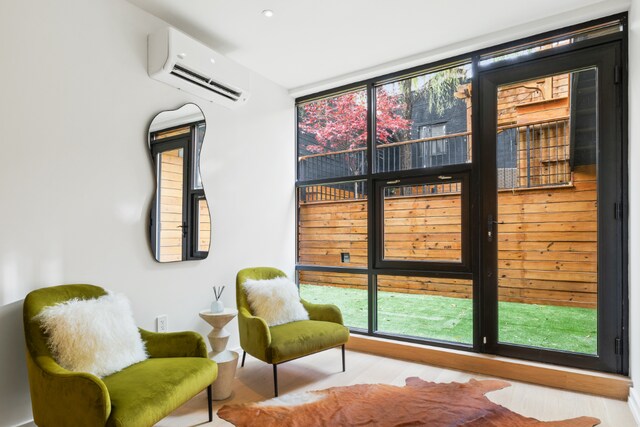 living area featuring a wall unit AC and light wood finished floors