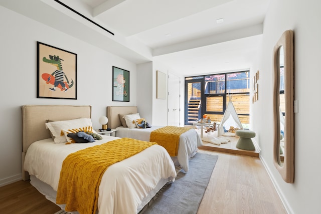 bedroom with access to exterior, light wood-style flooring, and baseboards