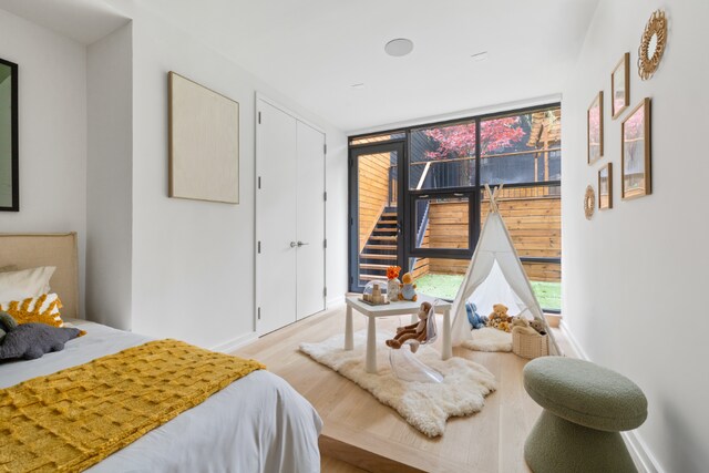 bedroom with light wood finished floors, baseboards, and floor to ceiling windows