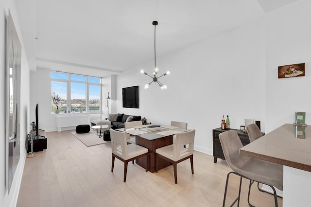 dining space with light hardwood / wood-style flooring and a notable chandelier