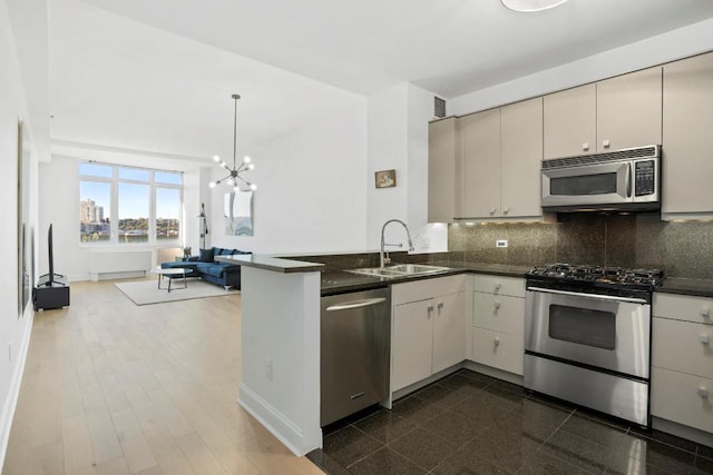 kitchen featuring sink, decorative backsplash, a notable chandelier, kitchen peninsula, and stainless steel appliances