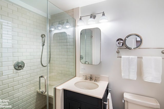 full bathroom with toilet, a stall shower, and vanity