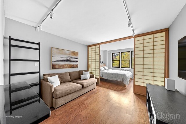 bedroom with hardwood / wood-style flooring and track lighting