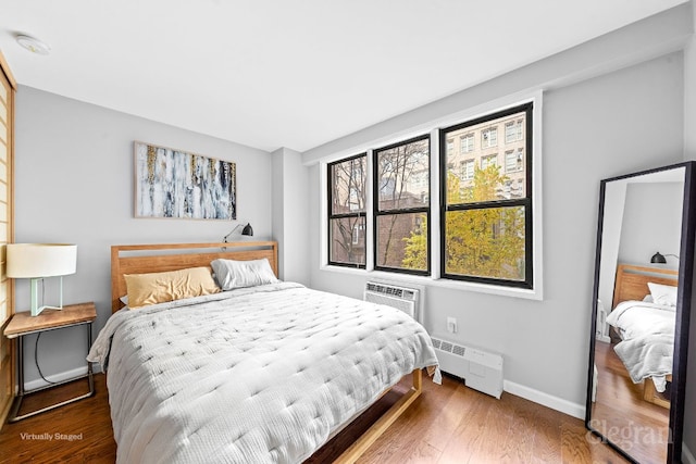 bedroom featuring a baseboard radiator, dark hardwood / wood-style floors, and a wall mounted AC